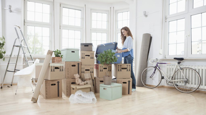 Femme arrangeant des cartons dans une pièce avec de grandes fenêtres